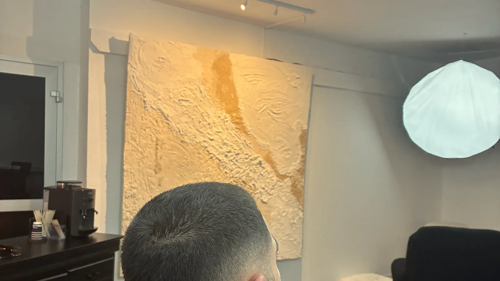 Le salon Oihan Barber : le grand tableau texturé beige et la lampe globe